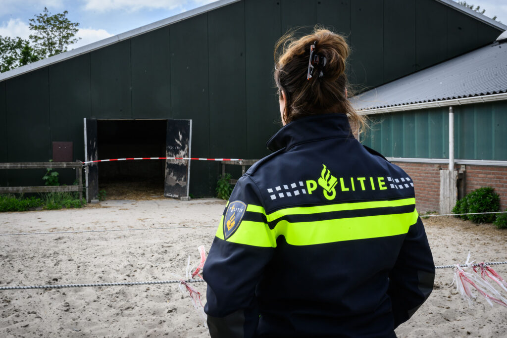 Politie die voor een loods staat die af is gesloten met een afzetlint.